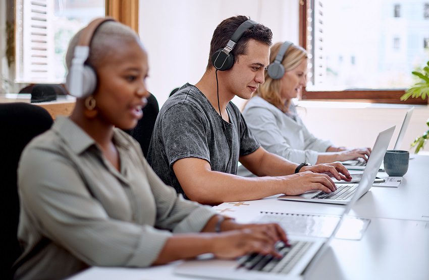 Office workers wearing headphones using laptops